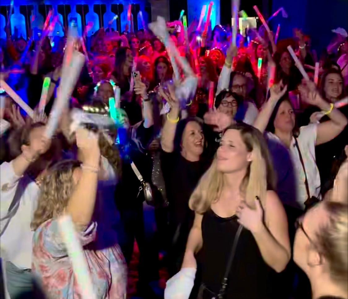 Ausgelassene Partygäste mit leuchtenden Schaumstoffstäben