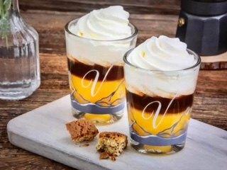 Zwei Dessertgläser mit Sahnehaube auf einem Holzbrett